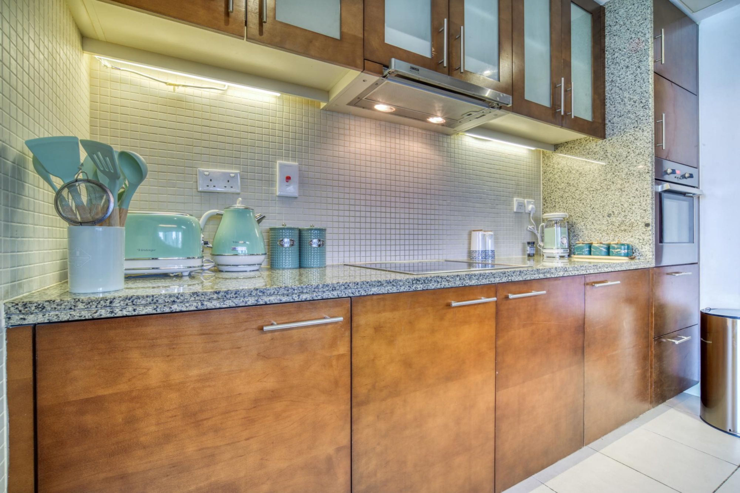 Una cocina con armarios de madera, encimera de granito y varios electrodomésticos.