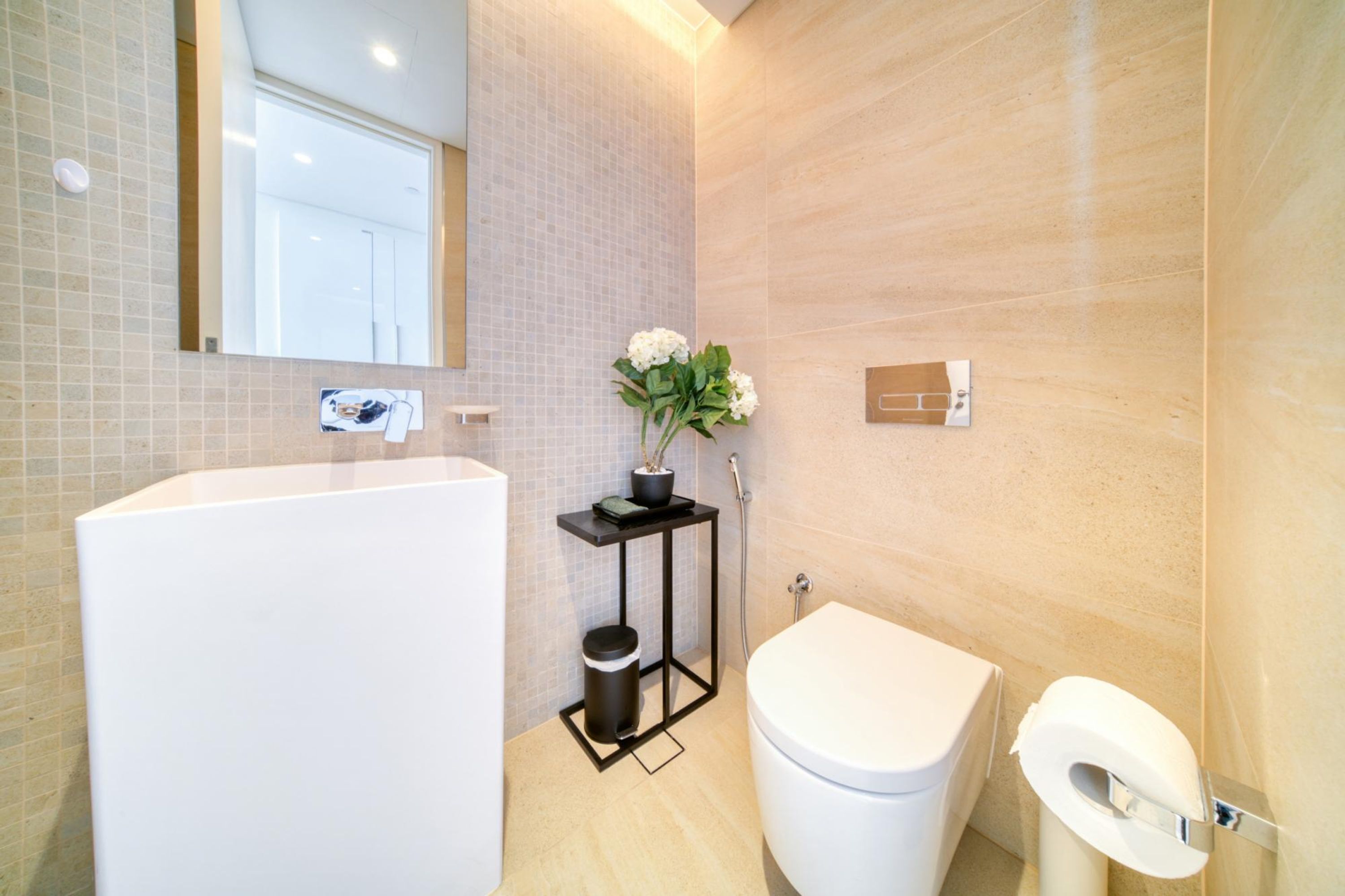 A modern bathroom with a white bathtub, a toilet, and a small table with a potted plant.