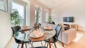 Ein modernes Wohnzimmer mit Essbereich, großen Fenstern, einem Flachbildfernseher und Blick auf die Stadt.