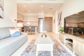 Una sala de estar moderna con un sofá, una mesa de centro, televisión y una cocina al fondo.