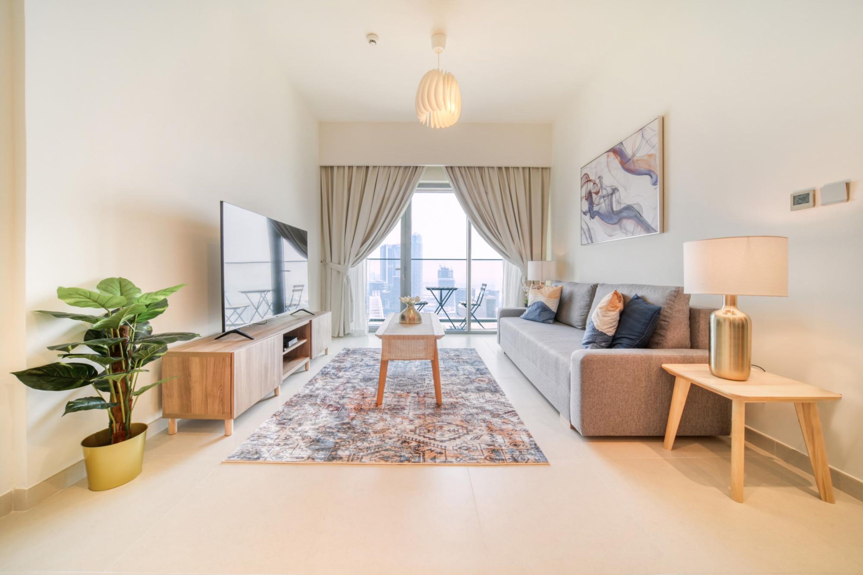 A modern living room with a sofa, TV, and a plant.