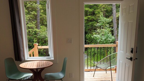 Une pièce comprenant un lit, une table ronde avec deux chaises, une fenêtre donnant sur un balcon et une porte menant à l’extérieur.