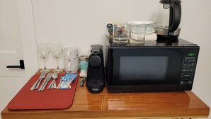 Un plan de travail de cuisine équipé d’un four à micro-ondes, d’une machine à café, ainsi que de divers verres et ustensiles.