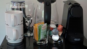 Une machine à café, une verseuse en verre, une tasse, un verre contenant des sachets de thé et un verre avec une tasse Starbucks.