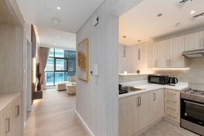 A modern kitchen with light wood cabinetry, a built-in microwave, and a stainless steel oven. - Prestigious 1BR Escape at The Palm (Dubai)