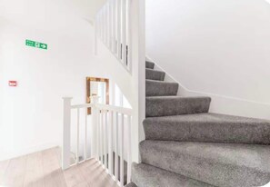 A staircase with grey carpeted steps and white railings.