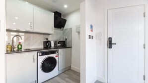 A compact kitchen with a washing machine, a microwave, and a coffee maker.