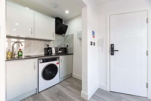 A compact kitchen with a washing machine, a microwave, and a coffee maker.