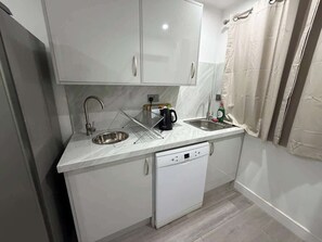 A compact kitchen with two stainless steel sinks, a coffee maker, and a dishwasher.