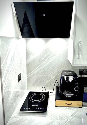A kitchen with a black induction cooktop, a Bosch coffee maker, and a wooden tray.