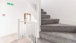 Eine Treppe mit grauen Teppichstufen und weißen Geländern.