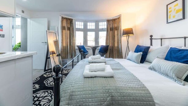 Ein Hotelzimmer mit Bett, Schreibtisch, Stuhl, Lampe und einem fensterbepflanzten Fenster.