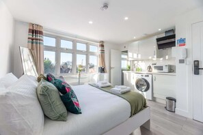 Hotelkamer met een bed, een wasmachine, een magnetron en uitzicht op het omliggende landschap.
