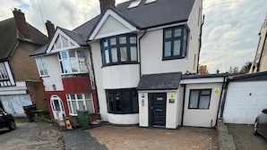 A residential house with a paved driveway, a garage, and a small garden. - Modern Surrey Studio - Easy Access to London (Surrey)