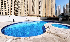 Un área de piscina con dos piscinas, rodeada de edificios altos.