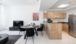 Eine moderne Küche mit Holzausstattung, einer integrierten Kücheninsel und einem Edelstahl-Kühlschrank.