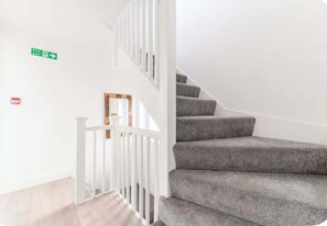 A staircase with grey carpeted steps and white railings.