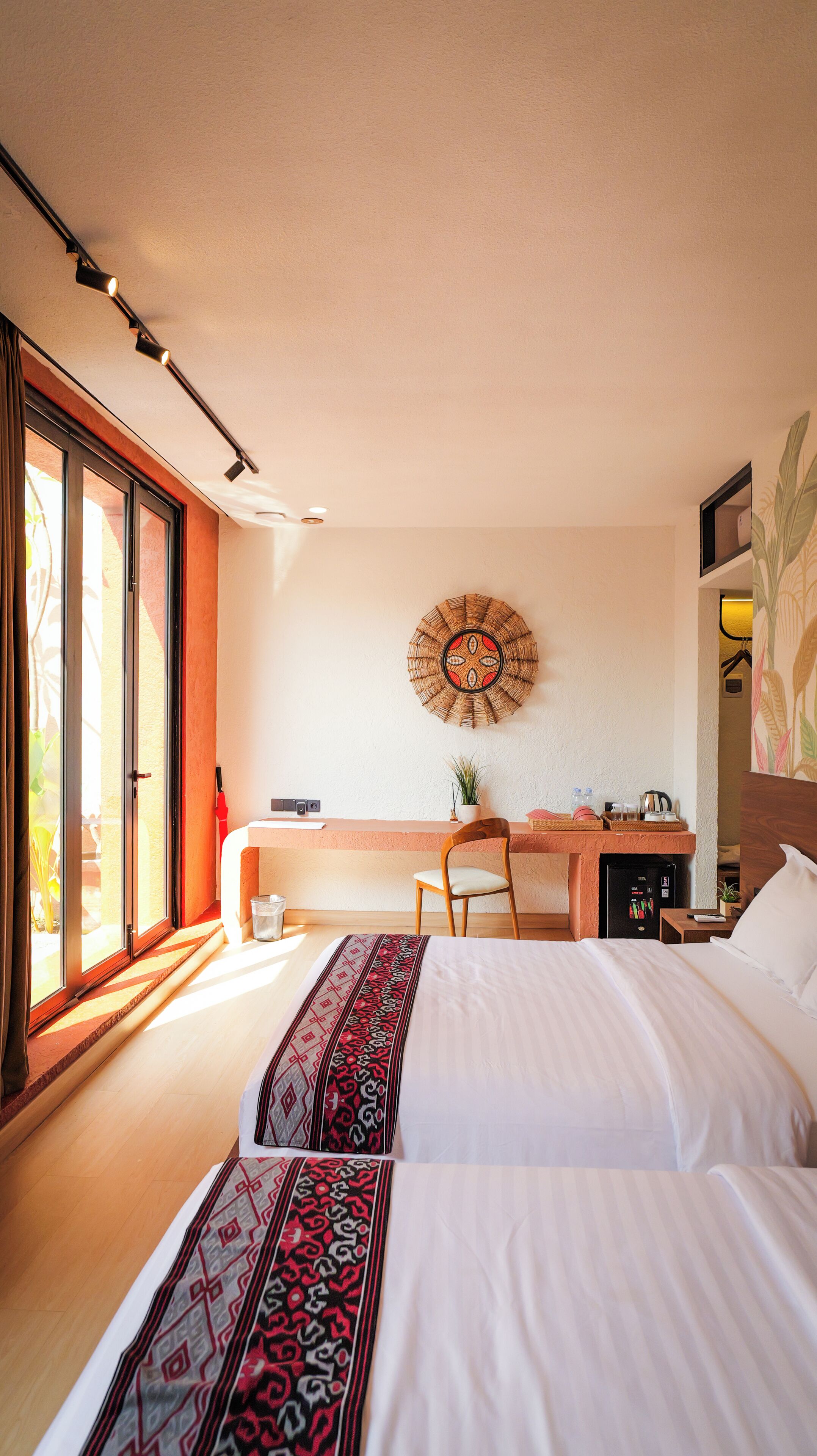 Une chambre d’hôtel comprenant un lit, un bureau, une chaise, une petite table et un objet décoratif fixé au mur.