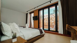 Ein modernes Hotelzimmer mit einem Bett, einem Fernseher, einem Nachttisch aus Holz und Blick auf einen Pool sowie Gebäude.