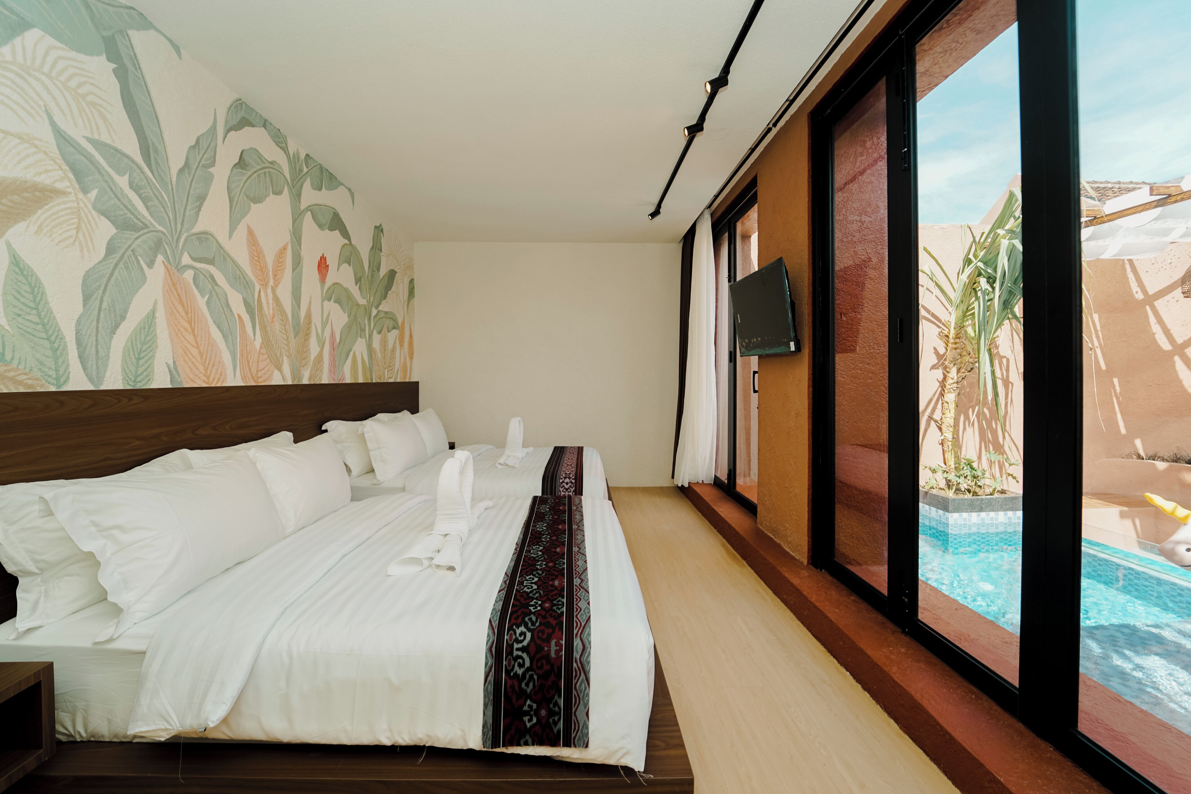A hotel room with a bed, a TV, and a view of a swimming pool.