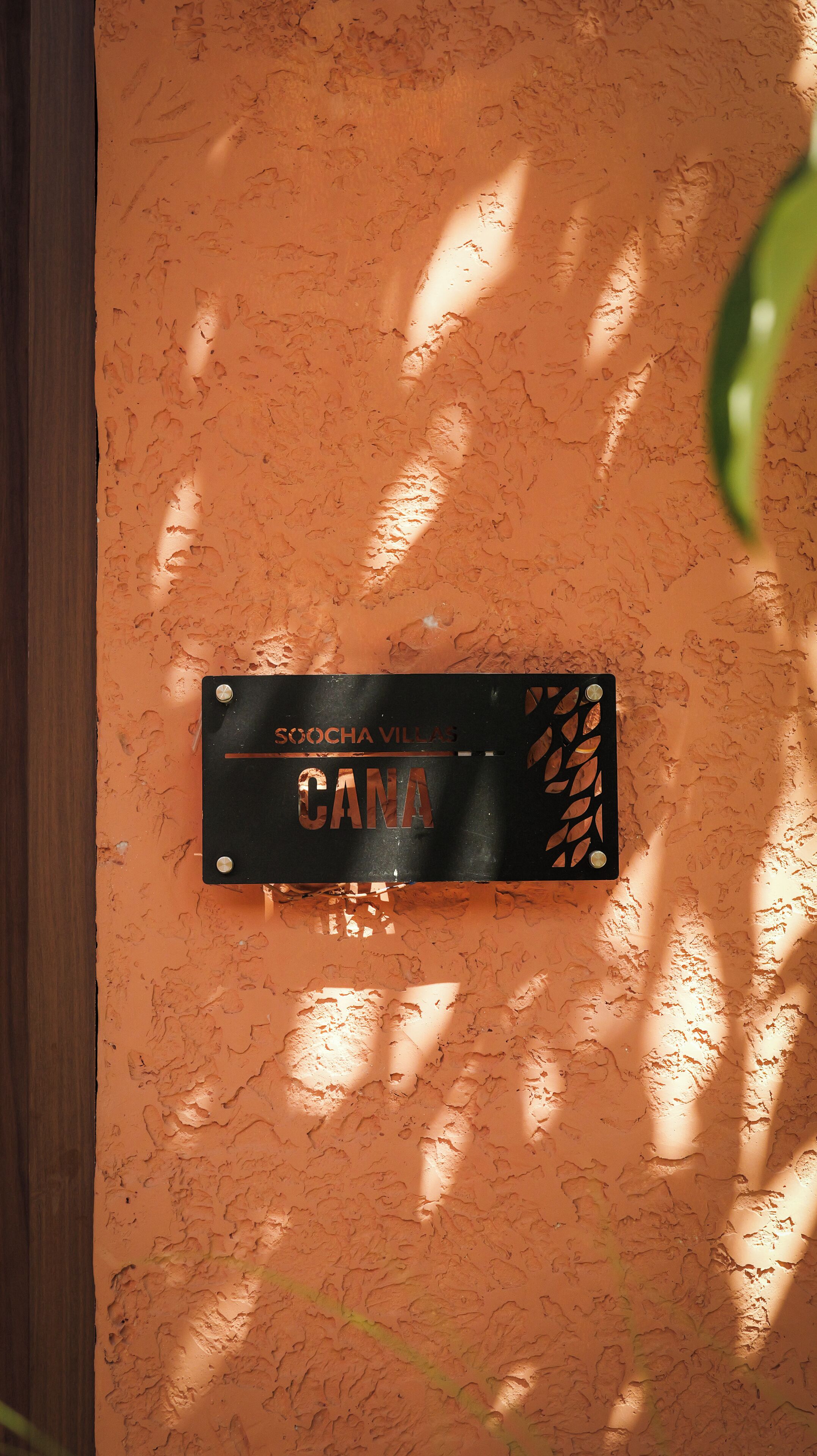 Un letrero con el texto 'Skocha Villas' y 'CANA' en una pared naranja texturizada.