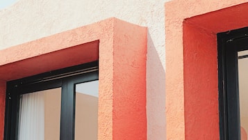 Eine Gebäudeansicht mit strukturierter Oberfläche und einem Fenster mit weißer Jalousie.