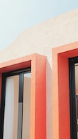 A building facade with a textured surface and a window with a white blind.