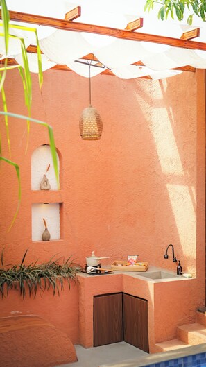 Un baño moderno con lavamanos integrado, una lámpara colgante y un estante pequeño con adornos.