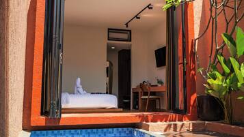 Una habitación de hotel moderna con diseño abierto, piscina y vistas al interior.