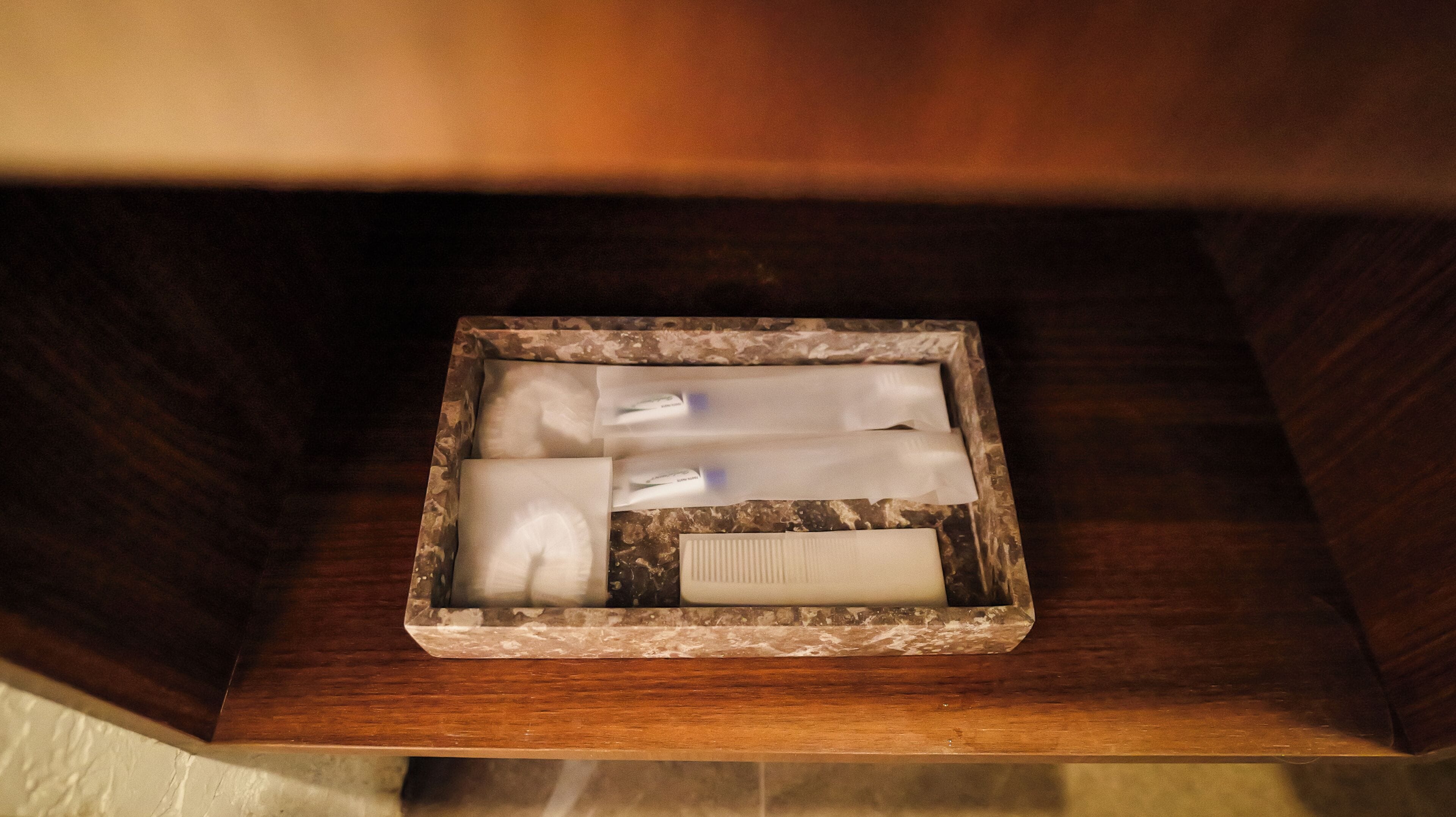 A wooden box with a marble-like pattern containing rolled-up towels and a white object.