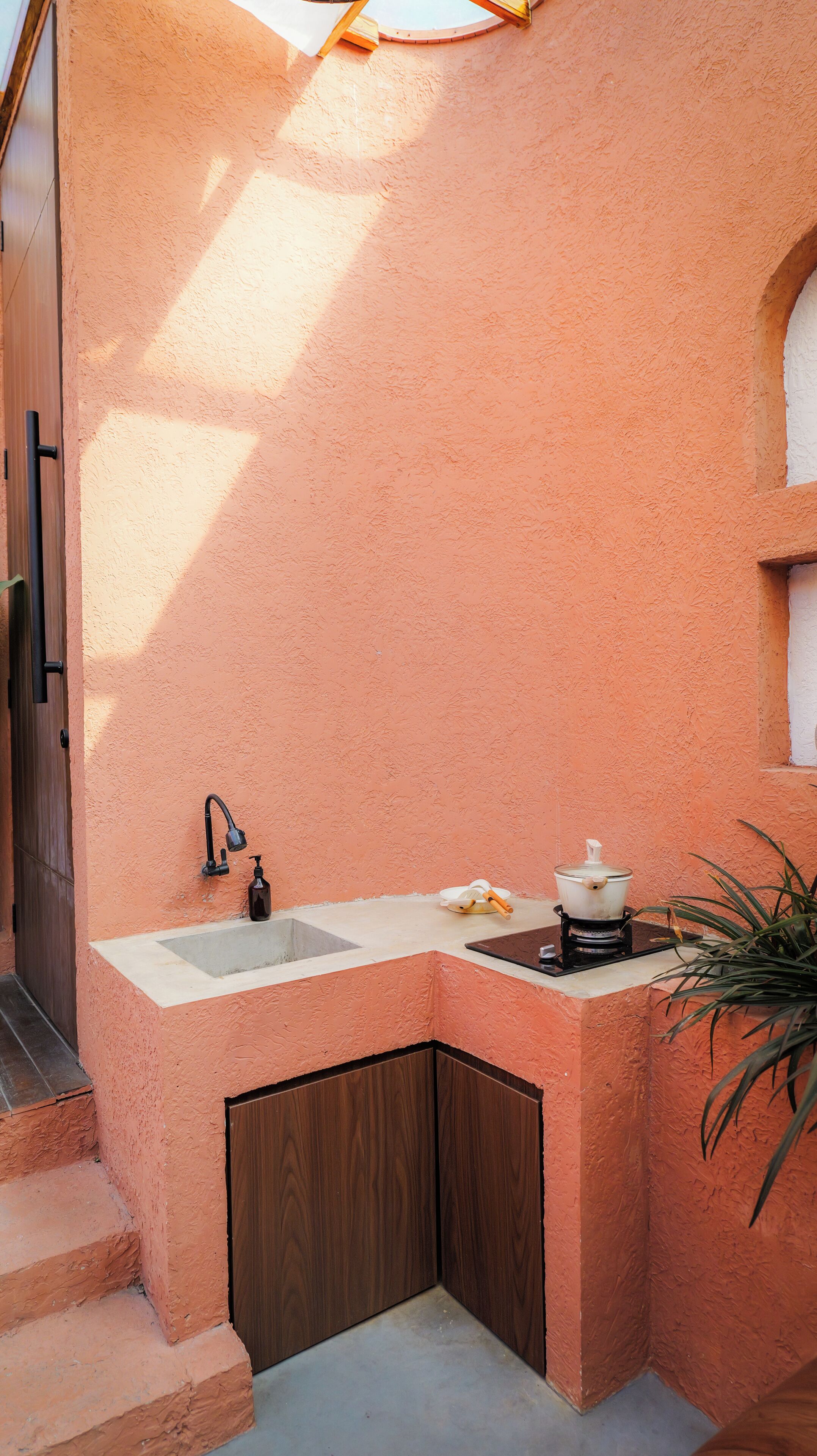 Une petite salle de bain d’angle avec un lavabo, une douche et une petite fenêtre.
