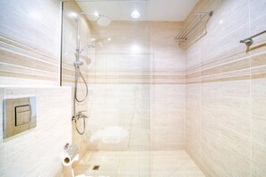 Een moderne badkamer met een douche, toilet en een handdoekrek.