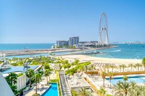 Un complejo turístico costero con una noria grande, una playa y una zona de piscina.