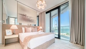 A modern hotel room with a large bed, a nightstand, a chandelier, a large window with a view of a Ferris wheel, and a balcony. - Classy Address JBR 3BR w/ Balcony and Beach Access (Dubai)