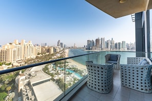Ein Balkon mit Blick auf eine Stadtlandschaft, einen Strand und einen Pool.