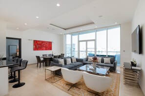 Ein modernes Wohnzimmer mit Sofa, Sesseln, einem Couchtisch und einem Essbereich.
