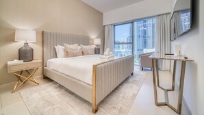 A modern hotel room with a large bed, a bedside table with a lamp, a small desk, and a large window offering a city view. - Modern Elegance w/ a New York Edge DIFC Apt (Dubai)