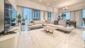 A modern living room with a large sectional sofa, a flat-screen TV, and a dining area with a table and chairs. - Modern Elegance w/ a New York Edge DIFC Apt (Dubai)