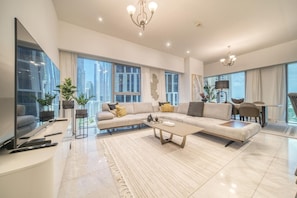 A modern living room with a large sectional sofa, a flat-screen TV, and a dining area with a table and chairs. - Modern Elegance w/ a New York Edge DIFC Apt (Dubai)