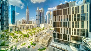 A modern cityscape with high-rise buildings, a central plaza with greenery, and a clear blue sky. - Modern Elegance w/ a New York Edge DIFC Apt (Dubai)