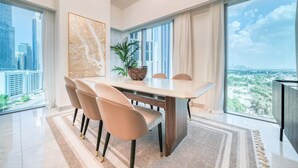 A modern dining room with a large table, chairs, and a view of the cityscape through large windows. - Modern Elegance w/ a New York Edge DIFC Apt (Dubai)
