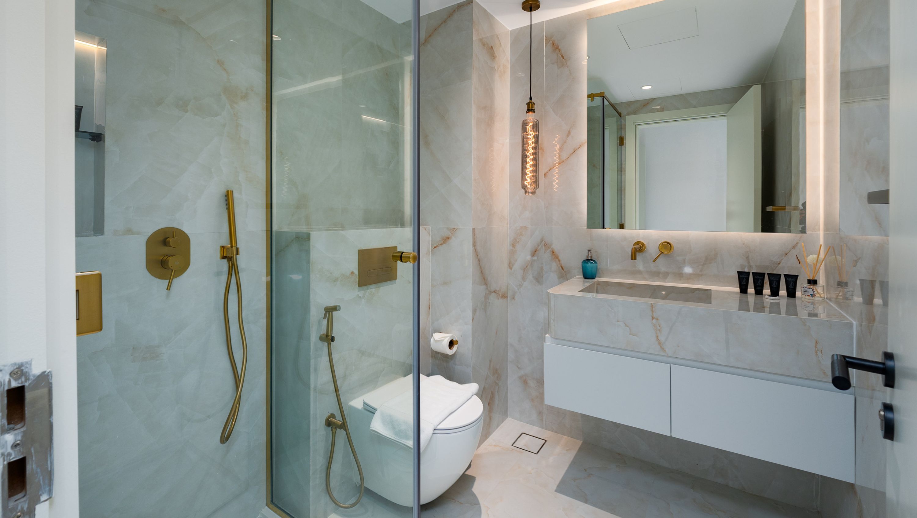 A modern bathroom with a glass-enclosed shower, a white toilet, and a vanity with a sink and mirror.