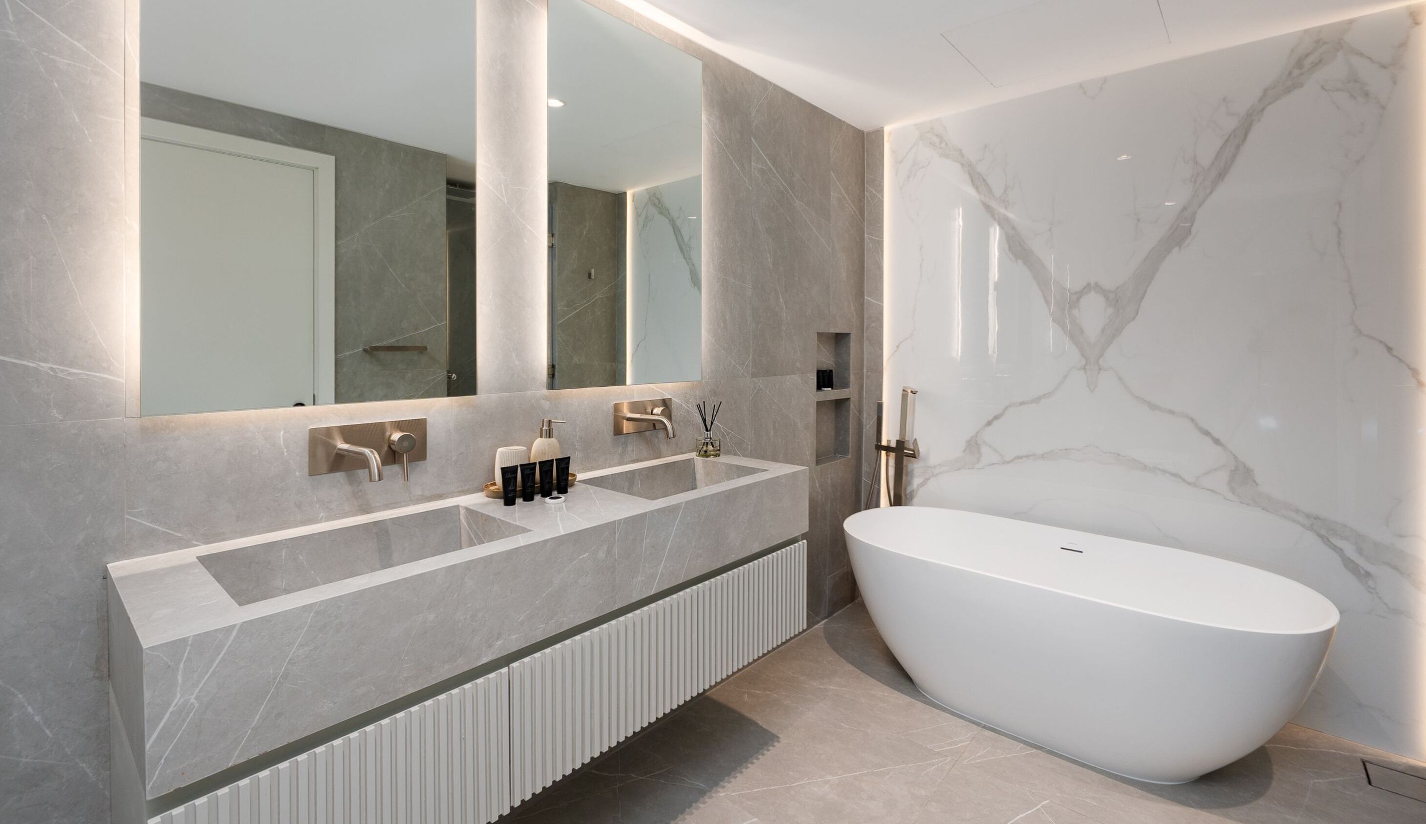A modern bathroom with a freestanding bathtub, a large mirror, and a vanity with a sink and towel rack.