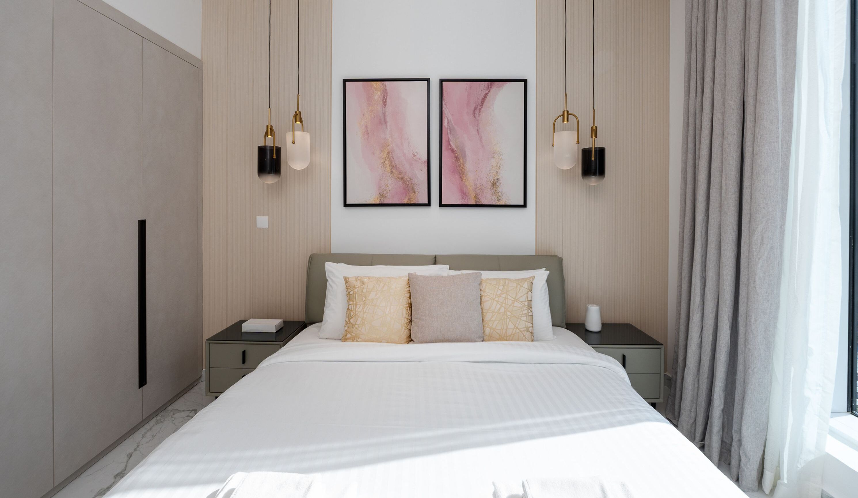 A modern hotel room with a large bed, two nightstands, a wardrobe, and abstract wall art.