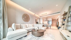 Ein modernes Wohnzimmer mit einer Eckcouch, einem runden Couchtisch und einem Essbereich im Hintergrund.