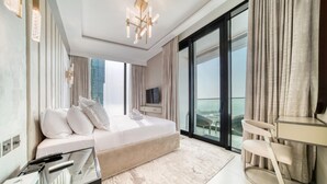 Ein modernes Schlafzimmer mit einem großen Bett, einem Fernseher, einem Schreibtisch und Blick auf die Stadt.