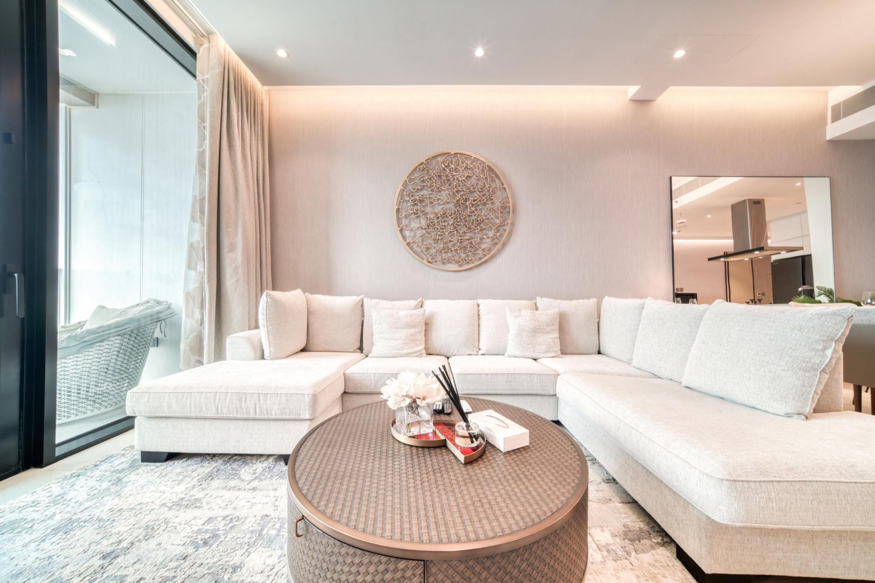 Un salon moderne avec un canapé d’angle, une table basse ronde et un élément décoratif mural.