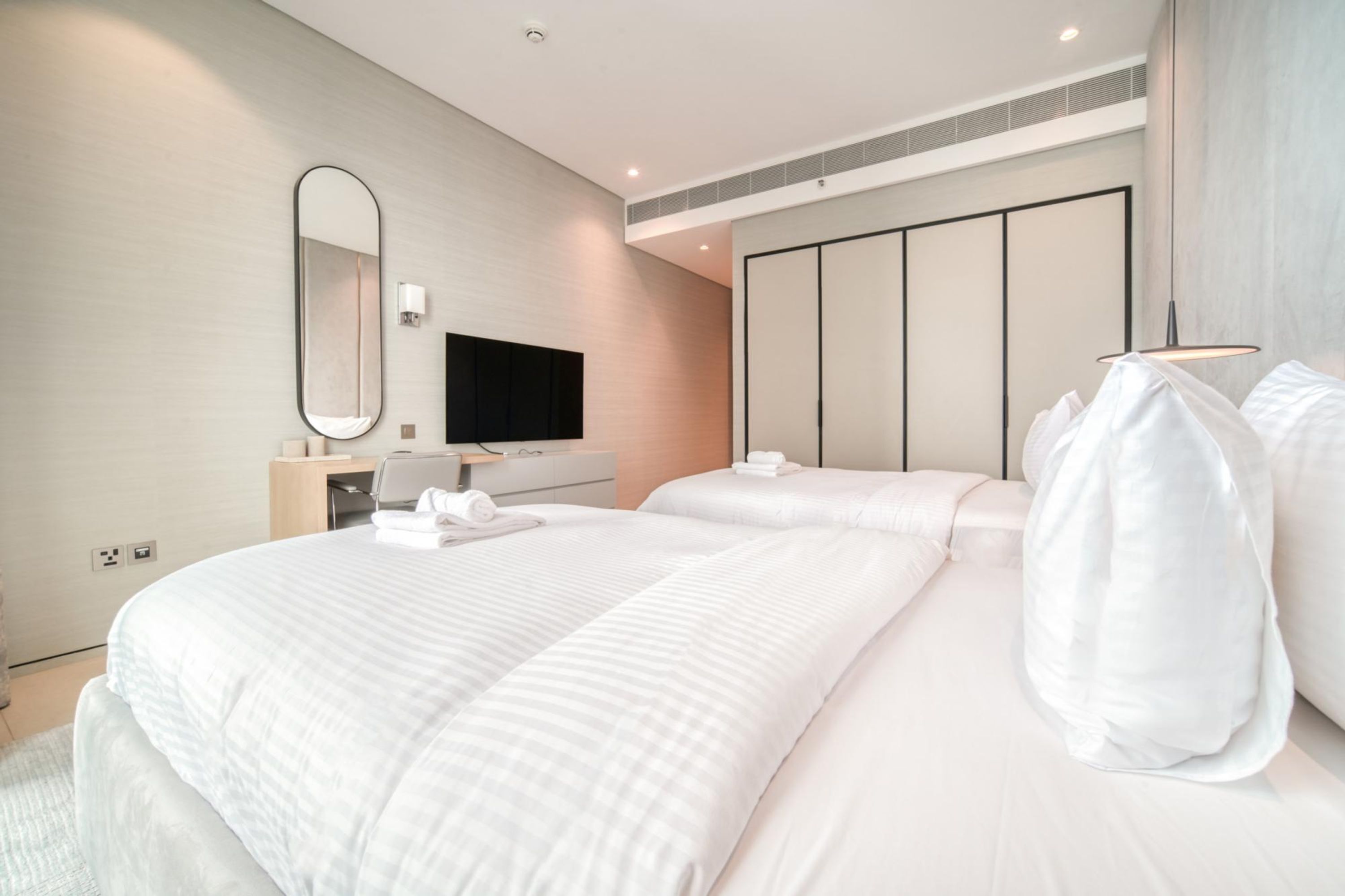 Une chambre d’hôtel moderne dotée d’un grand lit, d’une télévision à écran plat, d’une table de chevet et d’une armoire.