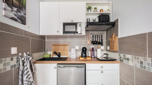 Een moderne keuken met witte kasten, een magnetron, een koffiezetapparaat en een vaatwasser.