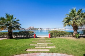 Un sendero que lleva a una playa con palmeras y una vista despejada del paisaje urbano costero.